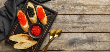 Ahşap arka planda kırmızı ve siyah havyarlı lezzetli bruschettalar.