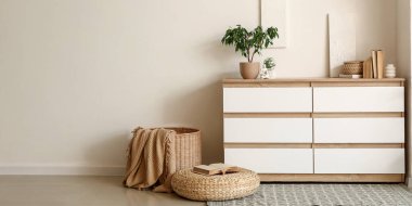 Beyaz duvarın yanında beyaz şifonyer olan ışık odasının içinde. Tasarım için pankart