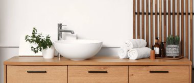 Lavabosu ve banyo aksesuarları olan şık ahşap bir şifonyer.