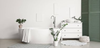 Beyaz şifonyer, küvet ve yeşil katlama ekranlı şık bir banyo.