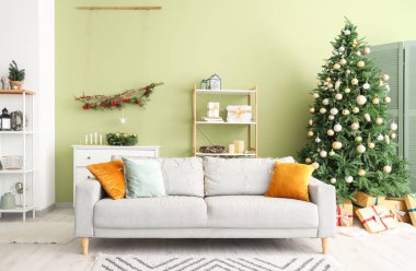 Rahat kanepesi ve Noel ağacı olan modern bir oturma odası.