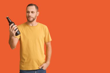 Turuncu arka planda soğuk bira şişesi olan genç adam.
