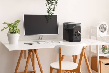 Modern bilgisayar ve taşınabilir güç istasyonu ile rahat çalışma alanı