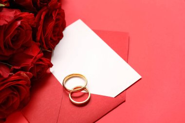 Zarflı güzel alyanslar ve arka planda kırmızı güller