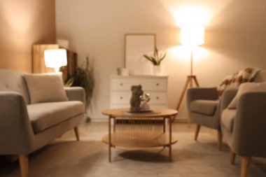 Gri koltuklu, koltuklu, parlak lambalı modern oturma odasının bulanık görüntüsü