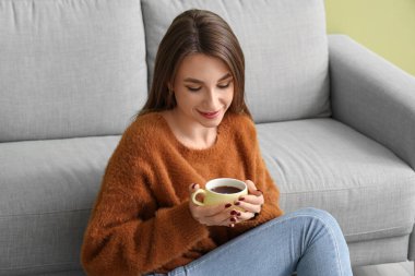 Evinde çay içen genç bir kadın.