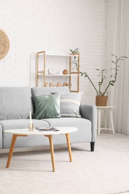 Gri kanepesi, masası ve raf ünitesi olan modern oturma odası.