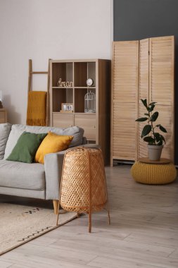 Gri kanepesi, lambası ve raf ünitesi olan rahat bir oturma odası.