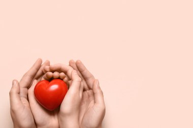 Pembe arka planda kırmızı kalp tutan kadın ve çocuğun elleri