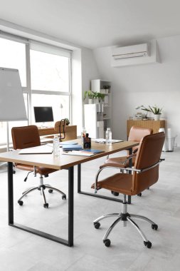 Masa bilgisayarı, kırtasiyesi ve koltukları olan ışık konferans salonu.