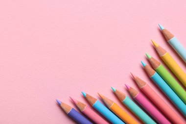 Pembe arka planda farklı renk kalemler, yakın plan