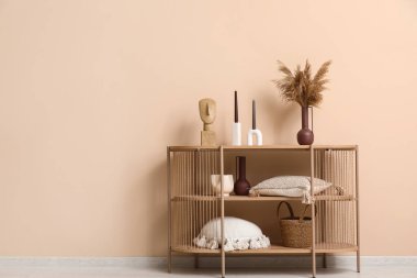 Vazoda otlu ahşap raf ünitesi, mumlar ve bej duvarın yanındaki oturma odasında dekor.