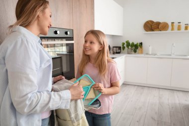 Mutlu bir anne ve kızı mutfaktaki beslenme çantasını hazırlıyorlar.