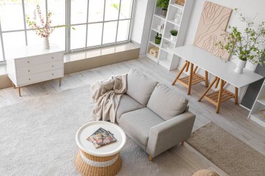 Kanepesi ve çiçek açan dalları olan modern bir oturma odası.