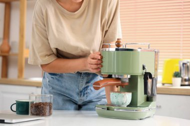 Mutfakta modern kahve makinesi olan güzel genç bir kadın, yakın plan.