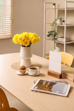 Oturma odasının iç tarafındaki yemek masasında güzel narsis çiçekleri olan vazo.