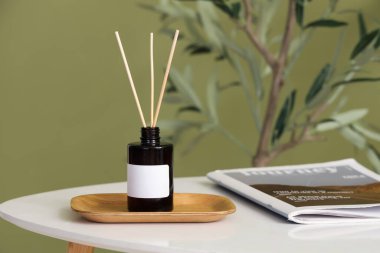 Reed dağıtıcı ve şarjör yeşil duvarın yanındaki sehpada.