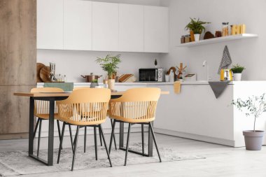 Mutfağın içinde yemek masası ve beyaz tezgahlar var.