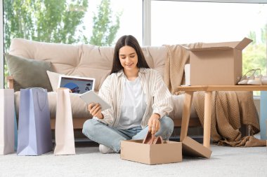 Tablet bilgisayarı olan ve evden online ayakkabı sipariş eden genç bir kadın.