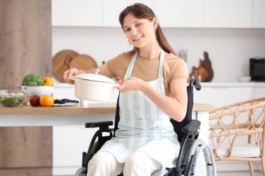 Tekerlekli sandalyedeki genç kadın evde tencere ile