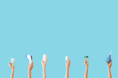 Lavman, matara, termometre ve mavi arka planda hapları olan kadın elleri.