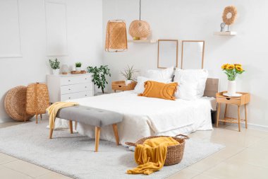 Yatak odasının içinde rahat bir yatak odası ve komodinin üzerinde güzel ayçiçekleri var.