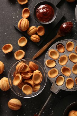 Lezzetli ceviz şekilli kurabiyeler, kaynatılmış süt ve koyu arkaplanda pişirme formu.