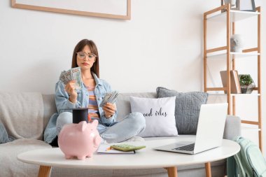 Parası olan düşünceli bir bayan öğrenci evdeki kanepede oturuyor. Eğitim tasarruf kavramı