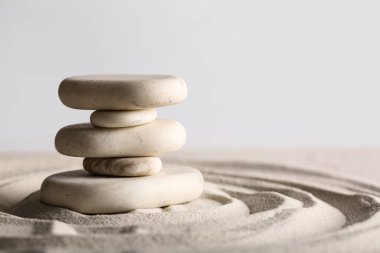 Kum üzerinde taş yığını ve ışık arka planında çizgiler. Zen kavramı