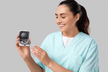 Gri arka planda işitme cihazı olan doktor.