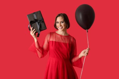 Kırmızı arka planda hediye kutusu ve hava balonu olan güzel genç bir kadın. Kara Cuma konsepti