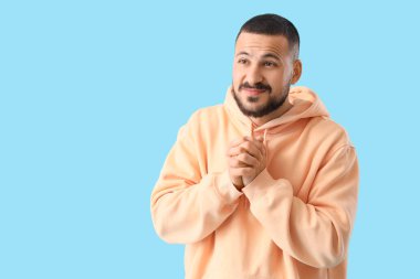 Mavi arka planda özür dileyen genç adam.