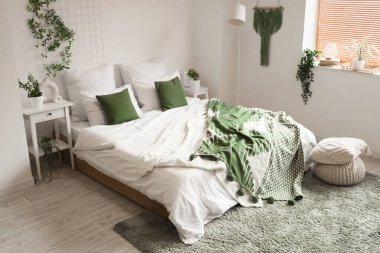 Masa ve yeşil bitkilerle aydınlık yatak odasının içi