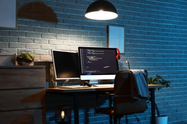 Çalışma yeri ve parlayan lambası olan karanlık programcı ofisinin içi.