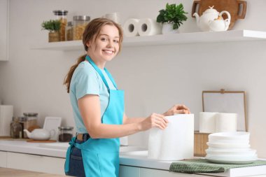 Mutfakta kağıt peçeteyle gezen genç bir kadın.