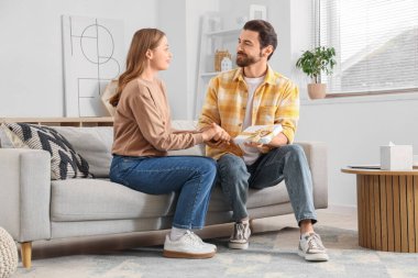 Hediyesi olan genç bir adam evinde karısından özür diliyor.