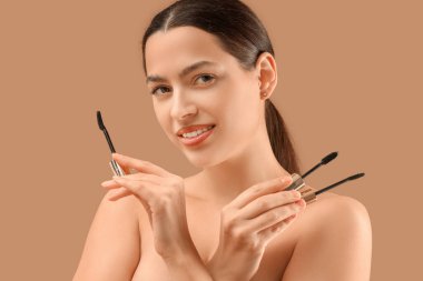 Bej arka planda rimel fırçası olan güzel bir genç kadın. Yakın plan.