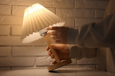 Evdeki parıldayan masa lambasında ampulü değiştiren kadın, yakın çekim.