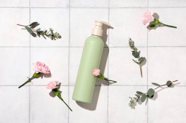 Duş jeli ve karanfil çiçekli kompozisyon beyaz karo arka planda, yakın plan