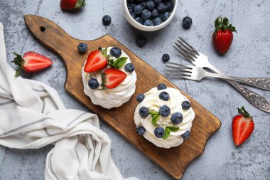 Tatlı Pavlova keklerinden ahşap tahta tahtada taze böğürtlen ve gri arkaplanda nane.