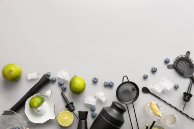 Farklı barmen aletleriyle kompozisyon, lezzetli kokteyller ve bej arka planda malzemeler.