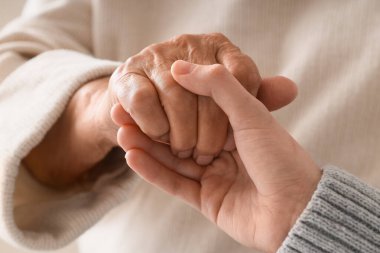 Bakıcısı el ele tutuşan son sınıf öğrencisi kadın, yakın plan. Bakım kavramı