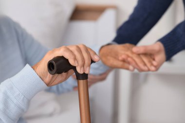 Bakıcı, son sınıf öğrencisine yataktan kalkması için yardım ediyor. Bakım kavramı