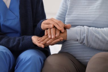 Bakıcı, yatak odasında el ele tutuşan yaşlı bir kadın, yakın çekim. Bakım kavramı