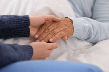 Yatak odasında el ele tutuşup, kapanış yapan yalancı, yaşlı bir kadın. Bakım kavramı