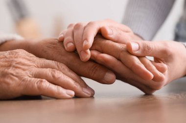 Mutfakta büyükannemin elini tutan genç bir kadın, yakın plan. Bakım kavramı