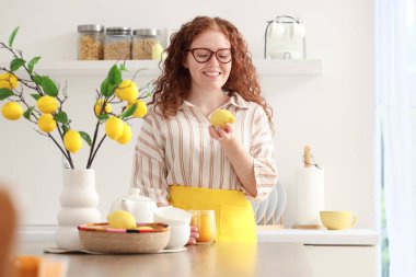 Mutfakta zerdeçal içkisi ve limonlu genç kızıl saçlı kadın.