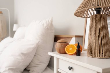 Yatak odasındaki masa üzerinde gerekli yağ ve portakallarla hava nemlendirici, yakın plan.