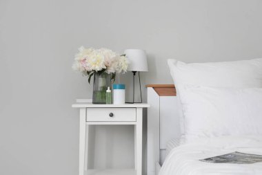 Hava nemlendirici, temel yağ, lamba ve vazo. Yatak odasındaki masasında şakayık çiçekleri var.