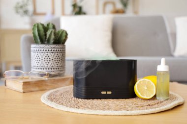 Oturma odasındaki masada gerekli yağ ve limonlarla hava nemlendirici, yakın plan.